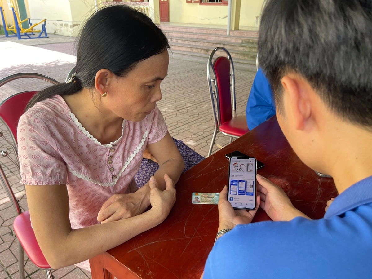 Thành viên tổ công nghệ số hướng dẫn người dân cài đặt ứng dụng số